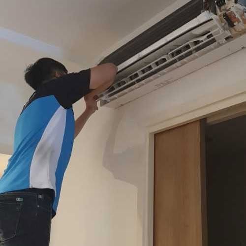 Aircon technician installing or repairing an indoor wall-mounted split air conditioner unit in Singapore.
