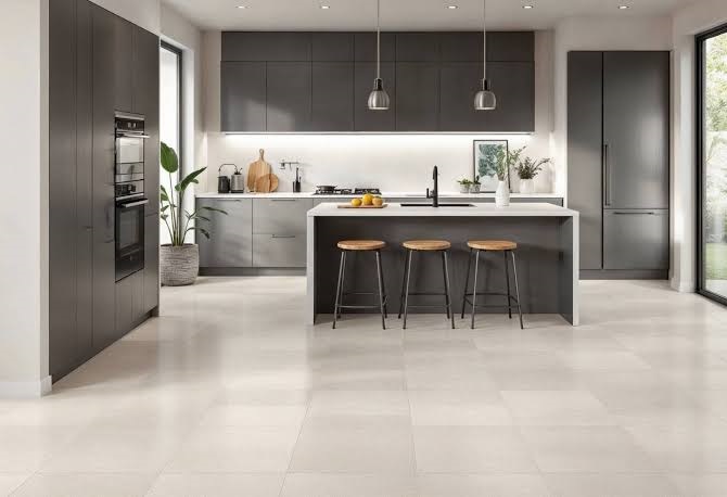 Modern dark grey kitchen interior design with a kitchen island, bar stools, under-cabinet lighting, and light grey tile flooring.